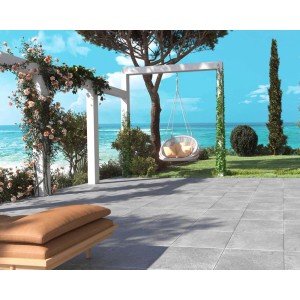 Piastrelle per esterni grigie t.b.t. su una terrazza con vista mare e sedia sospesa.