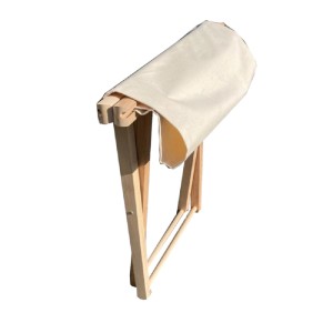 Sgabello da pianoforte piegato con rivestimento in tessuto beige.