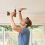 Uomo che fora il soffitto con trapano avvitatore a batteria Black+Decker BDCDD12K.