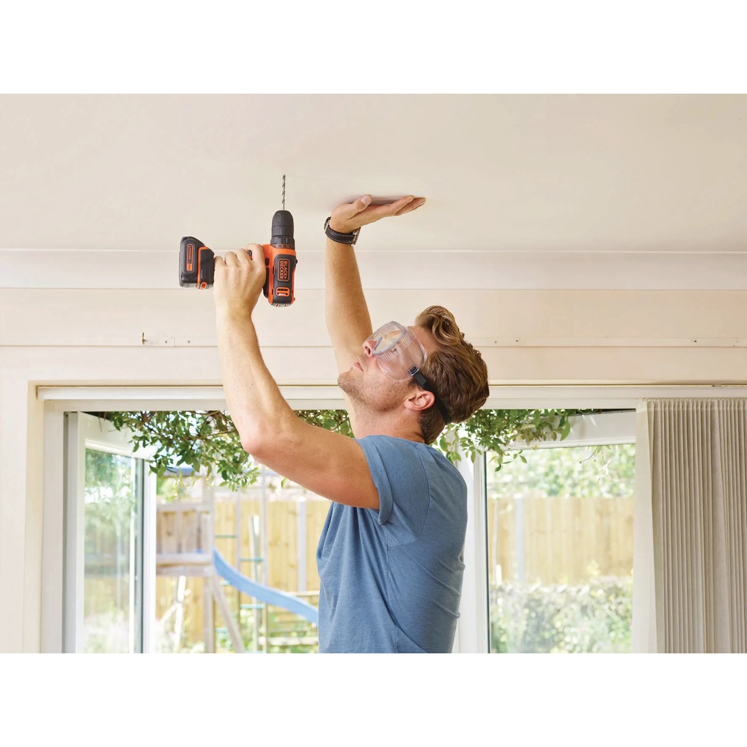 Uomo che fora il soffitto con trapano avvitatore a batteria Black+Decker BDCDD12K.