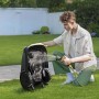 Uomo pulisce un robot tagliaerba t.b.t. nero con un tubo dell'acqua in giardino.
