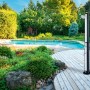 Doccia solare da esterno con doccetta (H 214 cm) accanto alla piscina su ponte di legno in giardino.