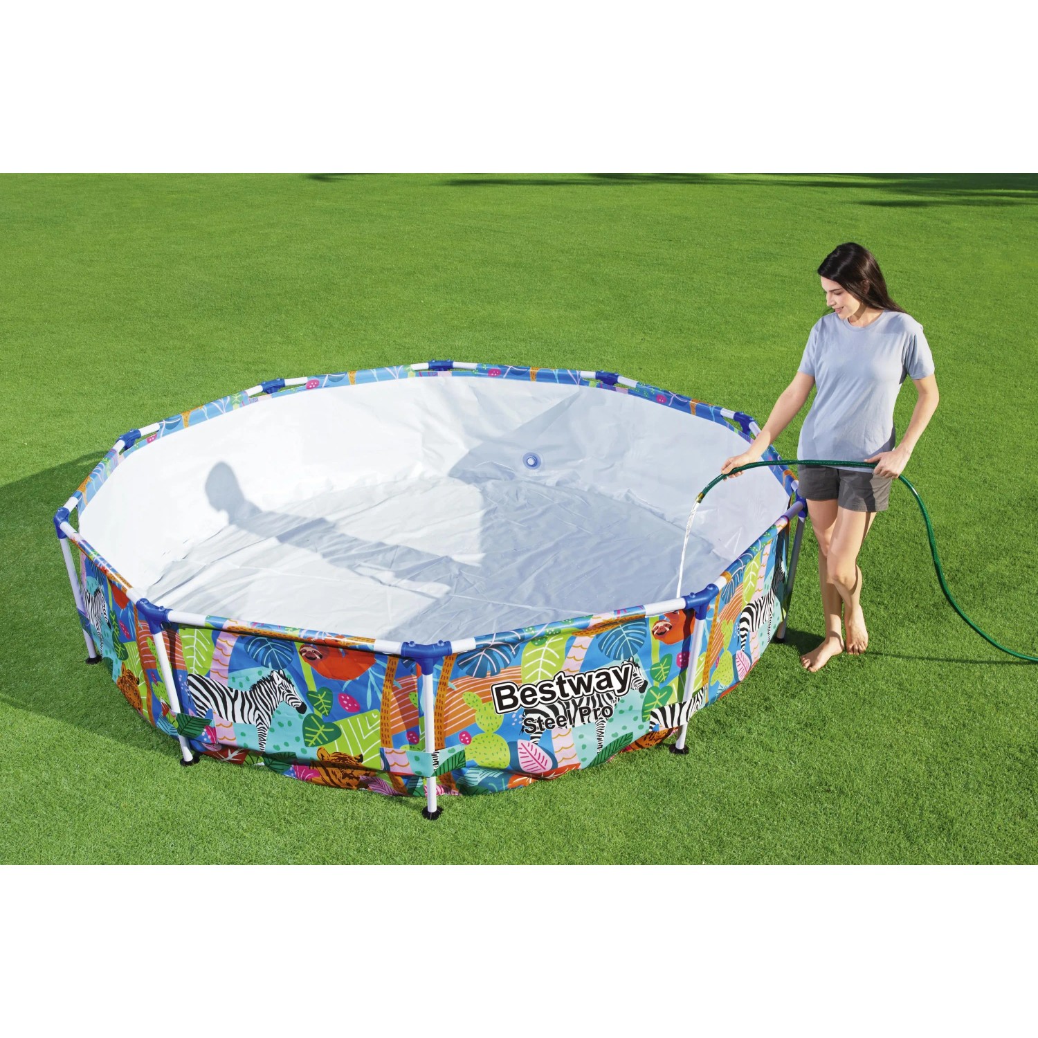 Piscina rotonda con struttura in acciaio e motivo giungla riempita con un tubo da giardino.