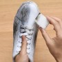 Pulizia di una scarpa in pelle bianca sporca con una spugna.