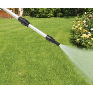 Lancia a spruzzo per la cura dell'auto in uso, getto d'acqua sul prato.