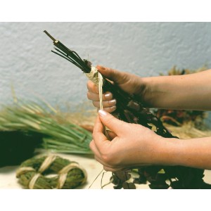 Mani che legano un bouquet con rafia naturale. Fibra naturale beige per decorazioni e artigianato.