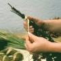 Mani che legano un bouquet con rafia naturale. Fibra naturale beige per decorazioni e artigianato.