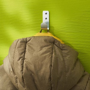 Giacca appesa a gancio per pannelli forati t.b.t. su parete verde.