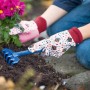 Guanti da giardinaggio rosa da bambino taglia 5 con rastrello in giardino.