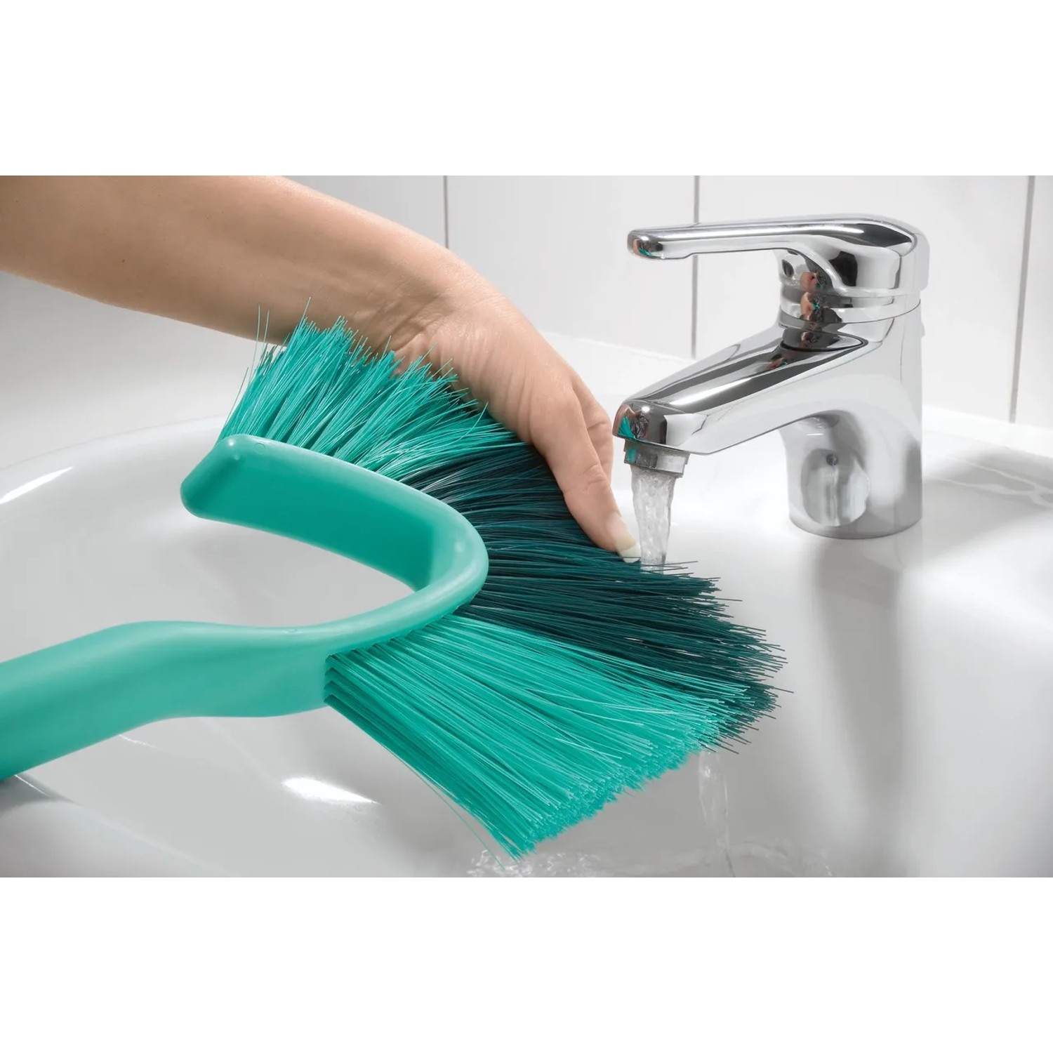 Leifheit Dusty spazzola manuale per pareti e soffitti sotto un rubinetto in un lavandino.