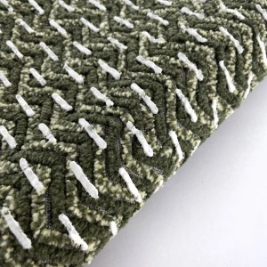 Dettaglio di un tappeto da bagno t.b.t. verde con motivo a zigzag bianco.