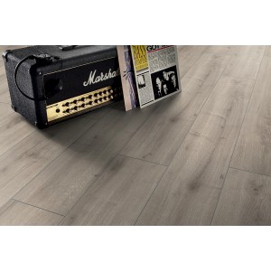 Pavimento laminato chiaro effetto legno, posato. Scena decorativa con amplificatore e disco.