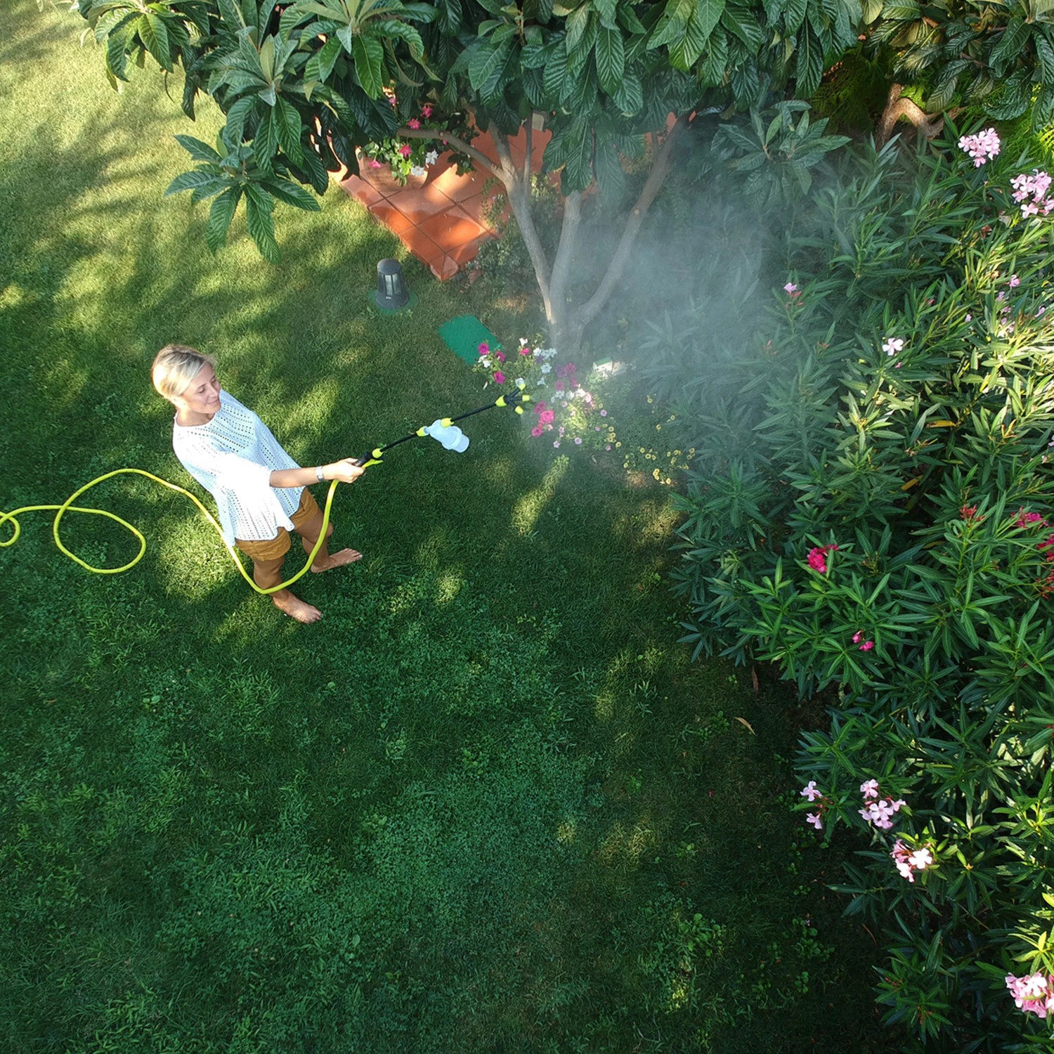 Donna che innaffia i fiori con una lancia a spruzzo t.b.t. in giardino.