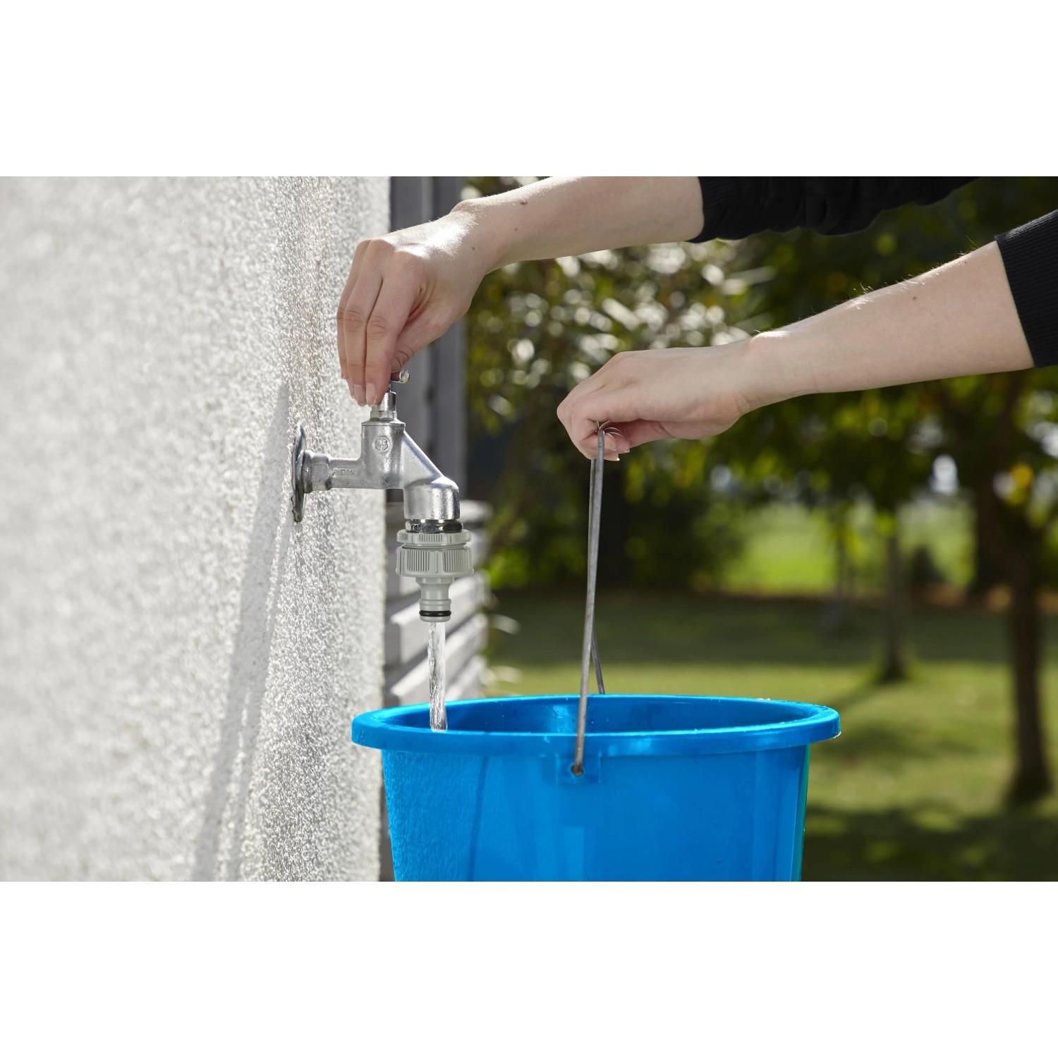 Rubinetto con raccordo irrigazione t.b.t. che riempie secchio blu.