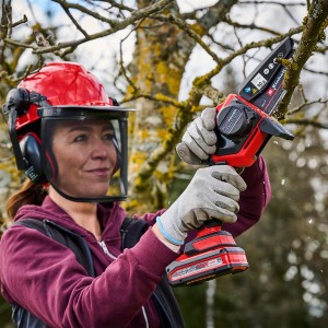 Donna che usa la motosega a batteria Einhell GE-PS 18/15 Li per potare un albero.
