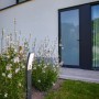Lutec LED da vialetto Kira (74cm) color antracite in giardino tra i fiori.