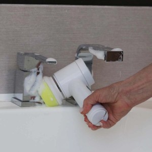 Spazzola di pulizia a batteria t.b.t. in azione sul lavandino con schiuma detergente.