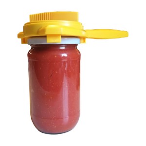 Apribarattolo a torsione giallo su barattolo con contenuto rosso per la conservazione in cucina.