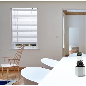 Persiana veneziana bianca t.b.t. alla finestra in una stanza luminosa.