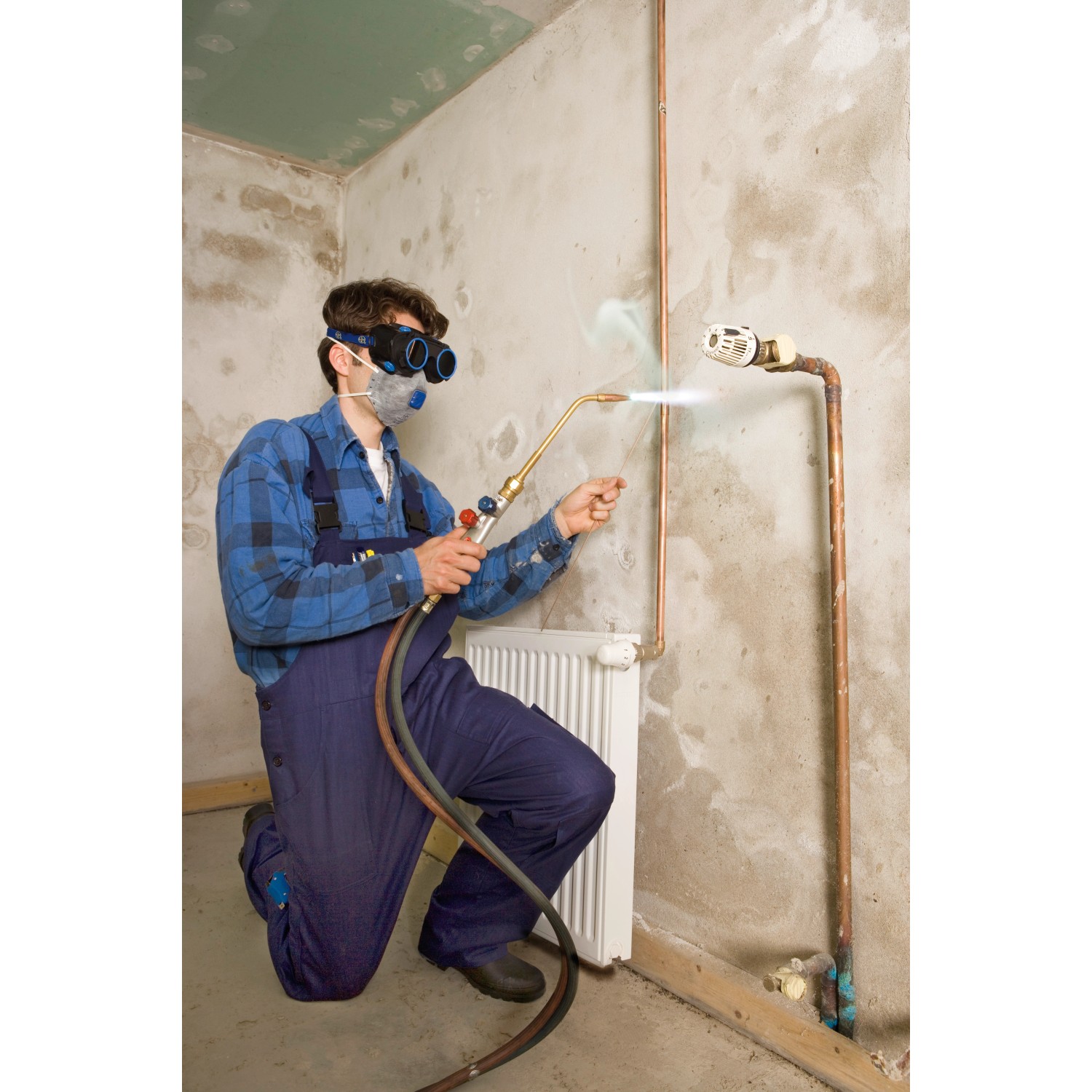 Artigiano che indossa maschera antipolvere LUX e usa cannello per saldare un tubo.