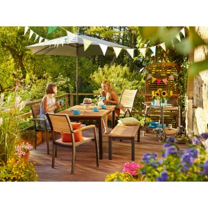 Scena da giardino con sedia impilabile in legno Bonlee FSC®, tavolo e decorazioni su terrazza.