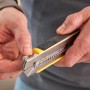 Cutter Stanley FatMax 18mm, nero-giallo, con caricatore di lame in mano.