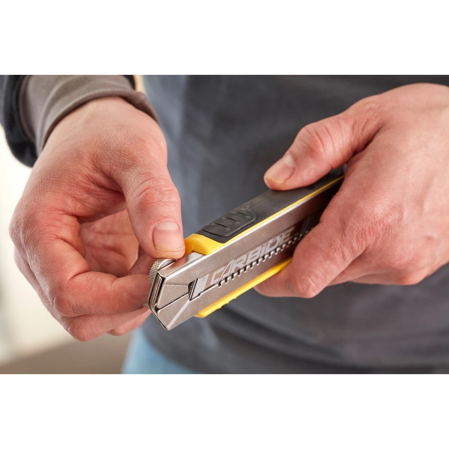 Cutter Stanley FatMax 18mm, nero-giallo, con caricatore di lame in mano.