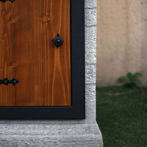 Dettaglio di una fontana da giardino con porta in legno e bordo in pietra.