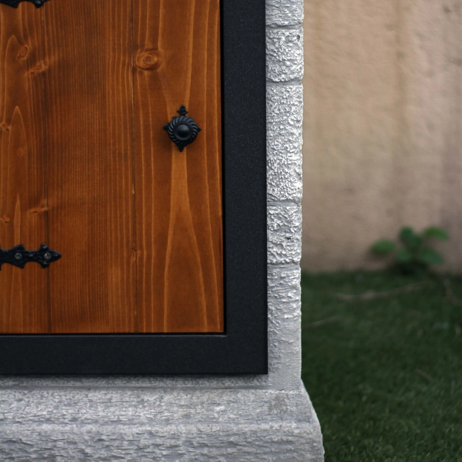 Dettaglio di una fontana da giardino con porta in legno e bordo in pietra.