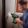 Uomo che fora un muro con il trapano a percussione a batteria Bosch UniversalHammer 18V. Include luce LED.
