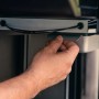 Mano estrae la vaschetta raccogli grasso sotto il barbecue a gas t.b.t.