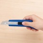 Mano che tiene un cutter LUX Classic 100 mm blu. Coltello con corpo in metallo e blocco lama.