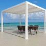Gazebo t.b.t. bianco con tetto a lamelle e tavolo da pranzo vista mare.