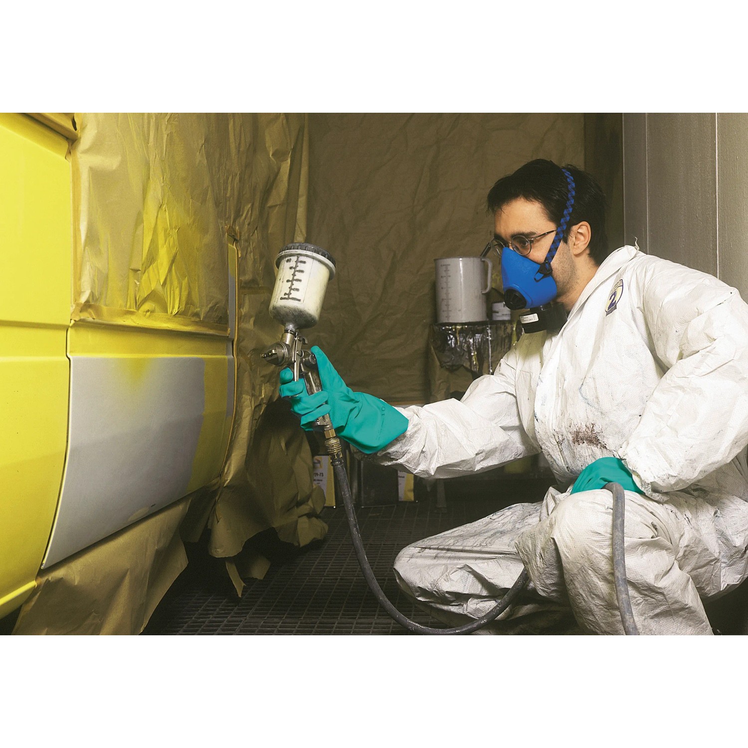 Uomo che vernicia l'auto con la semimaschera LUX A1 per la protezione respiratoria. Doppio filtro per una protezione ottimale.