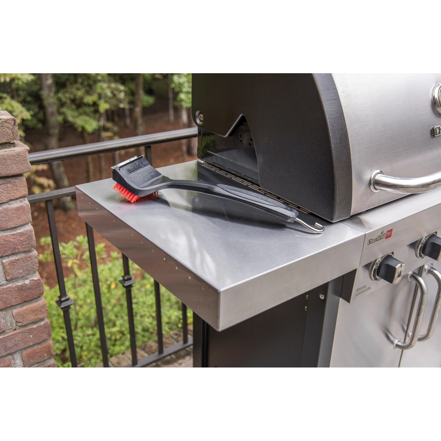 Spazzola per griglia Char-Broil Cool Clean Premium su un tavolo da grill. Utensile per griglia con raschietto e gancio.