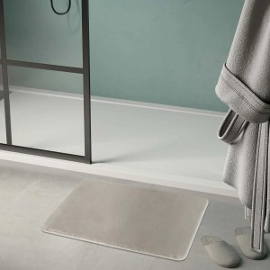 Tappeto da bagno beige t.b.t. davanti alla doccia con accappatoio e pantofole.