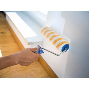 Rullo a dispersione LUX 18 cm liscio mentre dipinge una parete, a righe gialle e bianche.