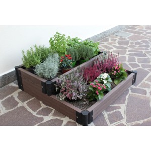 Aiuola rialzata in legno composito, piantata con erbe aromatiche e fiori.