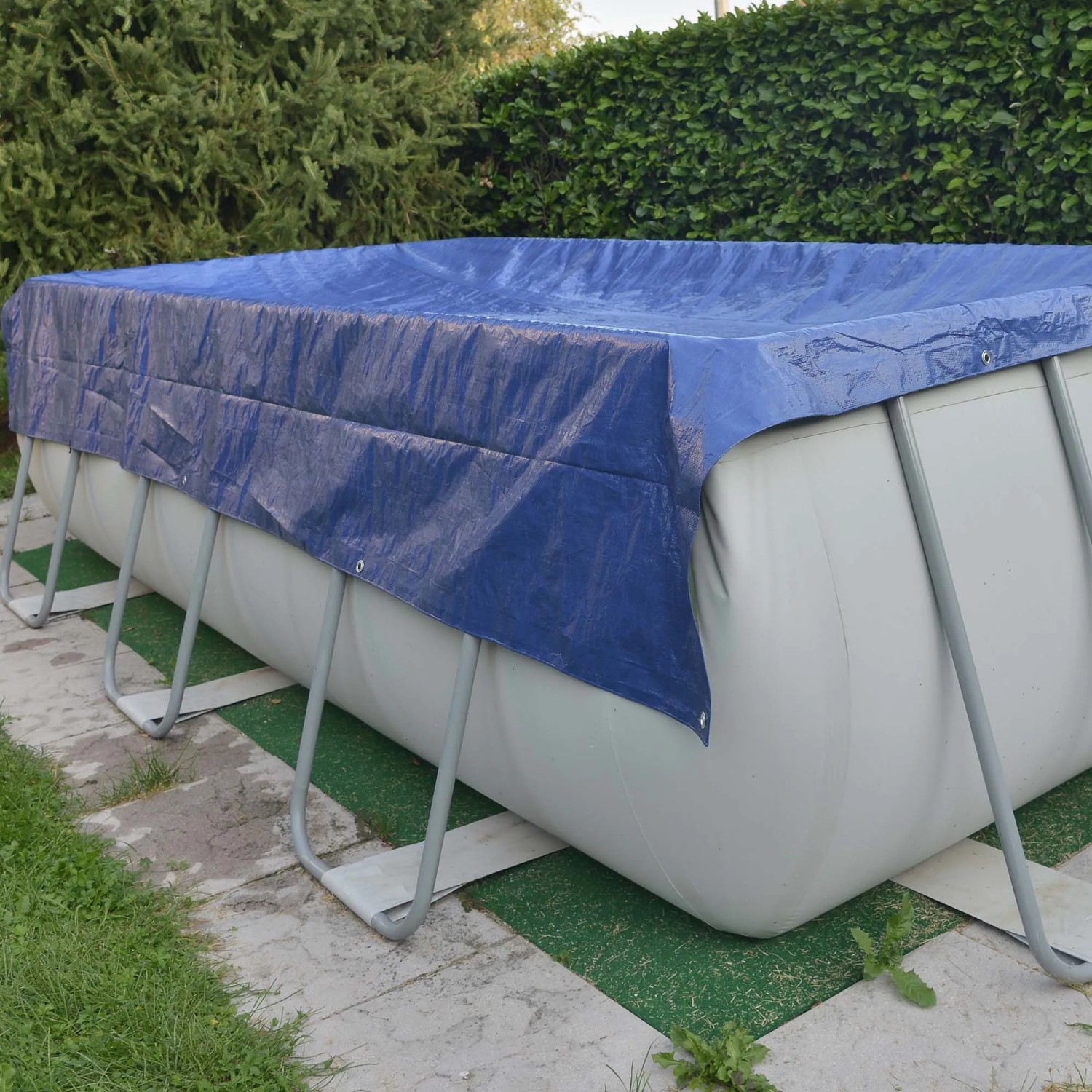 Telo di copertura blu t.b.t. che protegge una piscina rettangolare in giardino.
