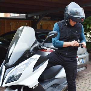 Uomo con casco da moto e abbigliamento da lavoro (t.b.t.) davanti allo scooter.