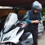 Uomo con casco da moto e abbigliamento da lavoro (t.b.t.) davanti allo scooter.