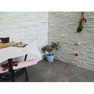 Rivestimento murale con pietre naturali bianche (Pietre naturali) in interni con tavolo e pianta.