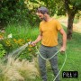 Uomo che innaffia il giardino con tubo per irrigazione t.b.t. e ugello a spruzzo.