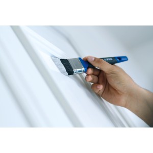 Mano che dipinge con pennello piatto LUX 60 mm. Pennello per vernice con impugnatura morbida blu.