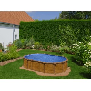 Grande piscina ovale fuori terra Gre Amazonia effetto legno con acqua blu in giardino.