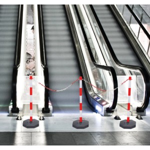 Paletti di delimitazione con catena di plastica rossa e bianca davanti alle scale mobili.