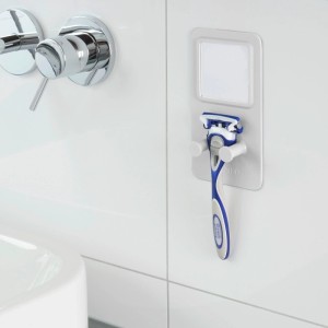 Accessorio da parete e contenitore t.b.t. con rasoio su parete bianca del bagno.