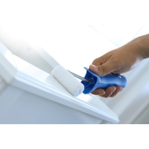 Rullo in feltro LUX 25 cm mentre vernicia una superficie bianca. Rullo per pittura con manico blu.