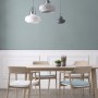 Sala da pranzo con tavolo, sedie e tre lampade a sospensione in bianco e grigio.