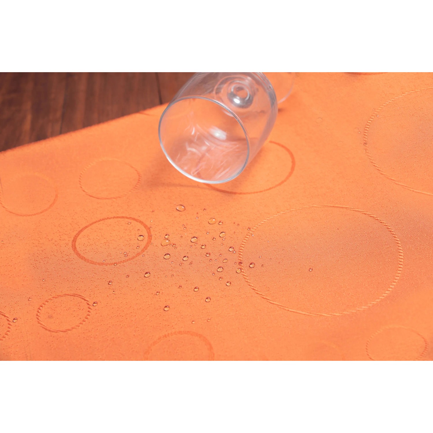 Tovaglia arancione con motivo a cerchi e gocce d'acqua, adatta per il negozio online OBI.